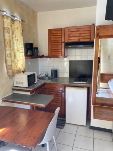 una cucina con mobili in legno, un tavolo e un forno a microonde di Les Emeraudes a Saint-Gilles-les Bains