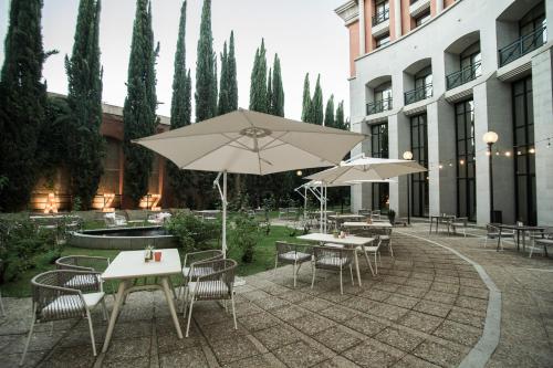 a patio with tables and chairs and umbrellas at AZZ Mérida Medea Hotel in Merida