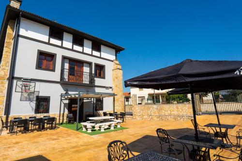 a building with chairs and tables and an umbrella at Paratene Ostatu Habitaciones in Erandio