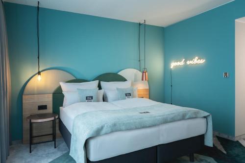a bedroom with a large bed with a blue wall at Holiday Inn - the niu, Cure Erlangen by IHG in Erlangen