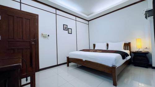 a bedroom with a bed and a wooden door at EZ House in Sukhothai