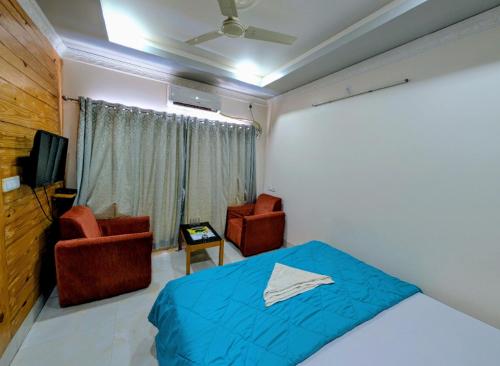 a bedroom with a bed and two chairs and a television at Dip Holidays in Shānti Niketan