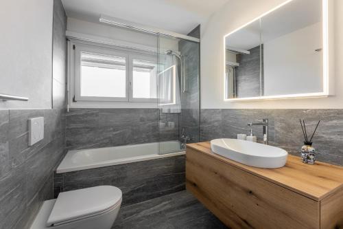 une salle de bain avec un lavabo, des toilettes et une baignoire dans l'établissement LAAX Homes - Haus Ner B 29, à Flims