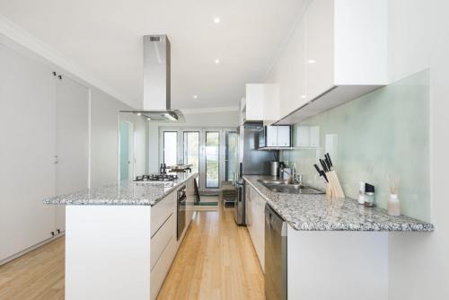 a kitchen with white cabinets and marble counter tops at Oceans View - Luxury Apartment with ocean views in Lancelin