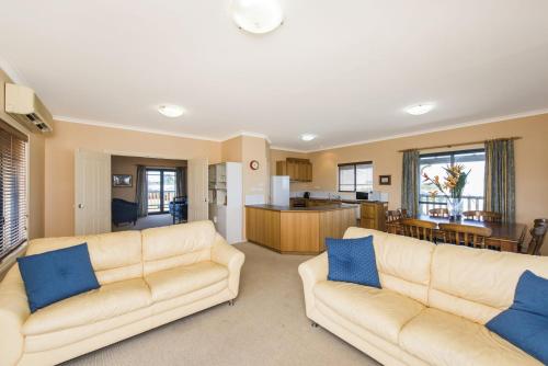 a living room with two couches and a kitchen at Sea Change - Spacious Family Holiday Accommodation Pet friendly in Ledge Point