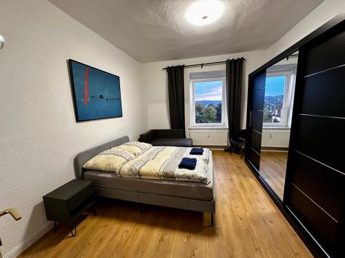 a bedroom with a bed and a couch and two windows at Wupa Flats in Wuppertal