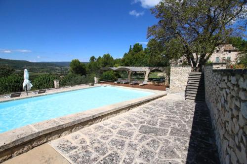 - une piscine avec un mur en pierre à côté d'une maison dans l'établissement Domaine de Saint Pons, à Villars