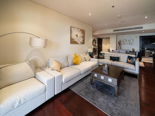 a living room with a white couch and a table at Ultra Luxury Palm Stay - Full Sea & Burj View - Royal Amwaj in Dubai