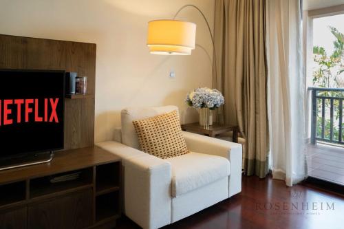 a living room with a white chair and a tv at Ultra Luxury Palm Stay - Full Sea & Burj View - Royal Amwaj in Dubai