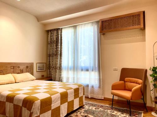a bedroom with a bed and a chair and a window at AARU Maadi Luxe Retreat in Cairo