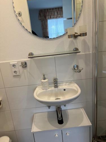 a white bathroom with a sink and a mirror at Gästehaus Elisabeth Bach in Mehring