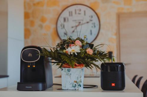 a coffee maker and a vase with flowers on a table at Villa au Petit Bonheur avec clim - Hameau au calme - piscine chauffée - pétanque in Moncrabeau