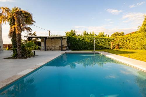 a swimming pool in a yard with a palm tree at Villa au Petit Bonheur avec clim - Hameau au calme - piscine chauffée - pétanque in Moncrabeau