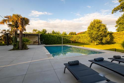 a swimming pool with two chaise lounges in front of a yard at Villa au Petit Bonheur avec clim - Hameau au calme - piscine chauffée - pétanque in Moncrabeau