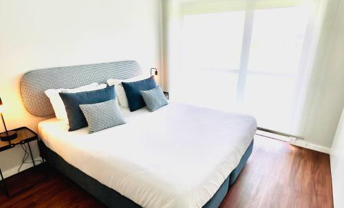 Un dormitorio con una cama con almohadas azules y blancas. en NearTheSEA by YoursPorto, en Matosinhos
