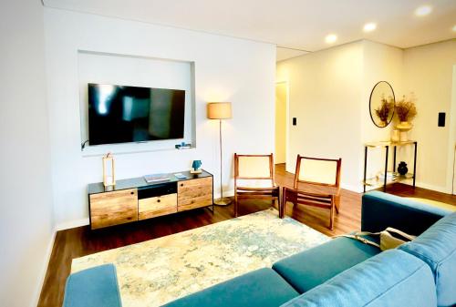a living room with a blue couch and a tv at NearTheSEA by YoursPorto in Matosinhos