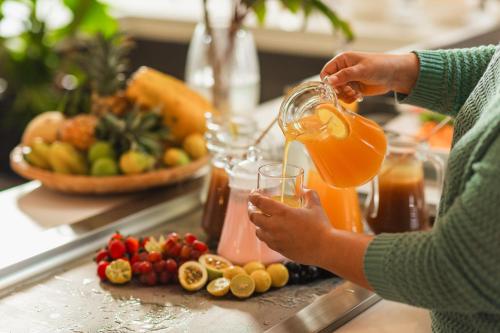 a woman is pouring a glass of orange juice at Cotton Bay Resort & Spa in Rodrigues Island
