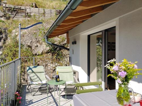 a patio with chairs and a table and a vase of flowers at Dascio Salute Ferienwohnung mit Panorama Balkon am See in Dascio