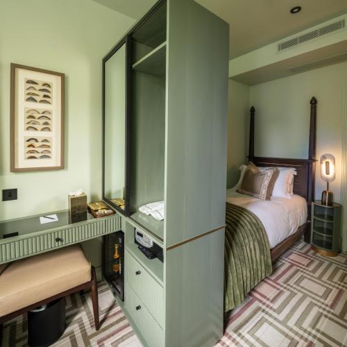 a bedroom with a bed and a desk with a mirror at Ellen Kensington in London