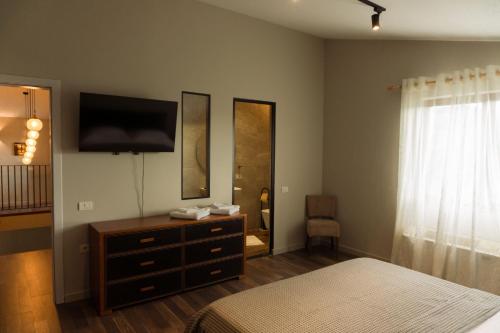 a bedroom with a bed and a dresser with a television at Secret Stone Villa in Tirana