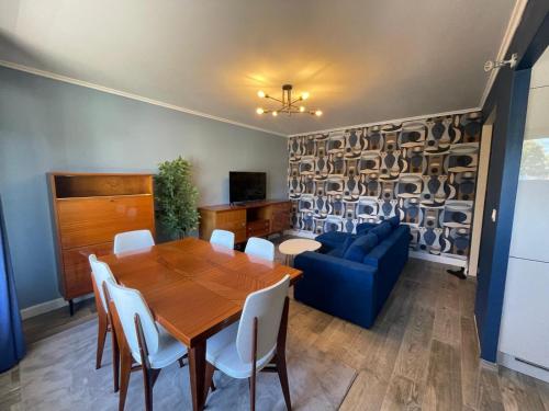 une salle à manger avec une table et un canapé bleu dans l'établissement Charming and Cosy Apartment near Paris, à Houilles