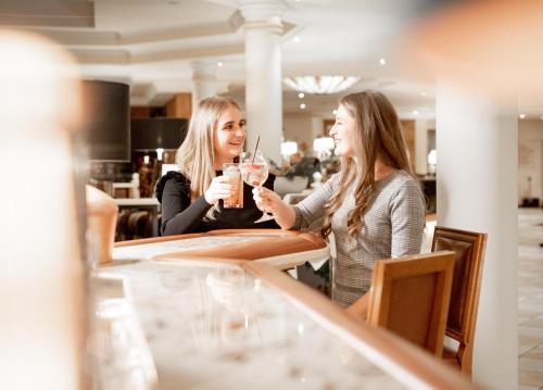 two women sitting at a bar drinking drinks at Avita Resort Bad Tatzmannsdorf in Bad Tatzmannsdorf