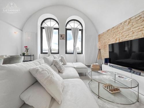 un salon blanc avec un canapé blanc et une télévision dans l'établissement Loft Lumineux Proche de la Cathédrale, à Metz