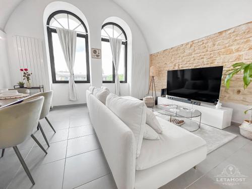 un salon blanc avec un canapé blanc et une télévision dans l'établissement Loft Lumineux Proche de la Cathédrale, à Metz