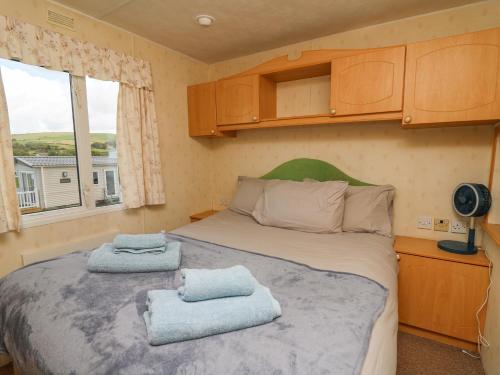 a small bedroom with a bed with towels on it at D12 Treetops in Aberystwyth