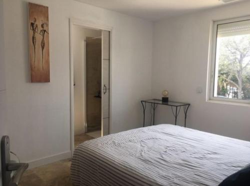une chambre blanche avec un lit et une fenêtre dans l'établissement Appart 3 chambres - Mer à pied, à Saint-Aygulf