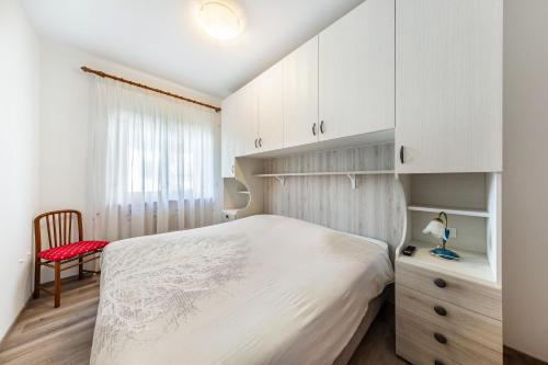 a bedroom with a white bed and a red chair at Casa Da Rin Emma in Auronzo di Cadore