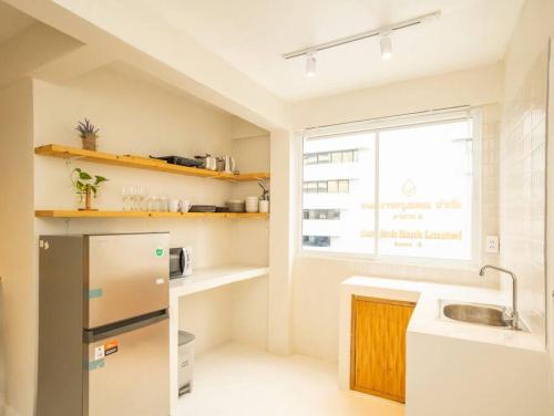 a small kitchen with a refrigerator and a window at Cozy 2-bedroom apartment in Silom city center - 6A in Bang Rak