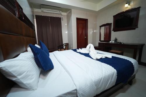 a bedroom with a large white bed with blue pillows at Mazus Urban Express in Mysore