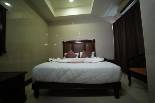 a bedroom with a bed with white sheets and pillows at Mazus Urban Express in Mysore