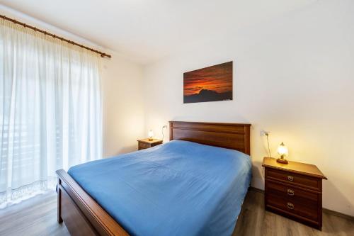 a bedroom with a blue bed and a window at Casa Da Rin Giulia in Auronzo di Cadore