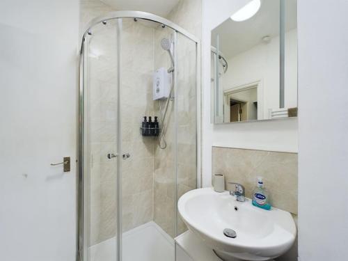 a white bathroom with a shower and a sink at Stylish Maisonette with Hot Tub in Brighton & Hove