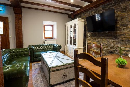 a living room with green leather furniture and a stone wall at Paratene Ostatu Habitaciones in Erandio