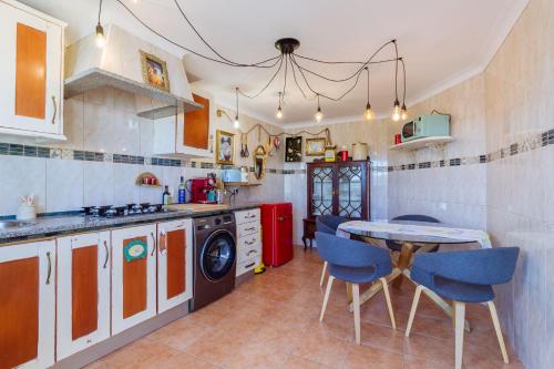 a kitchen with a table and blue chairs at Casa tempo e amor in Vila do Bispo