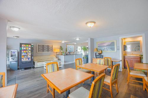 a dining room with tables and chairs and a kitchen at Liberty Inn and Suites Kissimmee near Disney World in Kissimmee