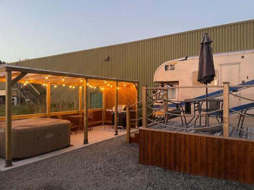 an rv parked next to a deck with a tent at Horse Truck Tiny Home with Hot Tub in Ashbourne