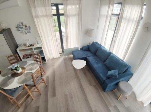 un salon avec un canapé bleu et une table dans l'établissement Ferienhaus Laura 70qm bis 5 Gäste mit Fass-Sauna, Whirlpool April bis Oktober, 75qm Terrasse und eingezäunten Garten Haustiere willkommen, à Sierosław