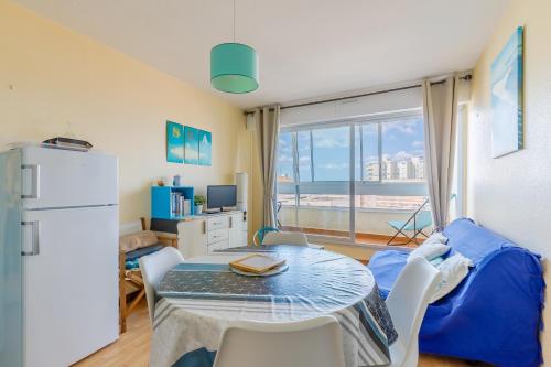 un salon avec une table et un réfrigérateur dans l'établissement Vue sur la Plage des Demoiselles - Appt vue mer, à Saint-Hilaire-de-Riez