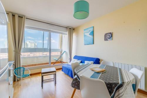 un salon avec une table et un canapé bleu dans l'établissement Vue sur la Plage des Demoiselles - Appt vue mer, à Saint-Hilaire-de-Riez