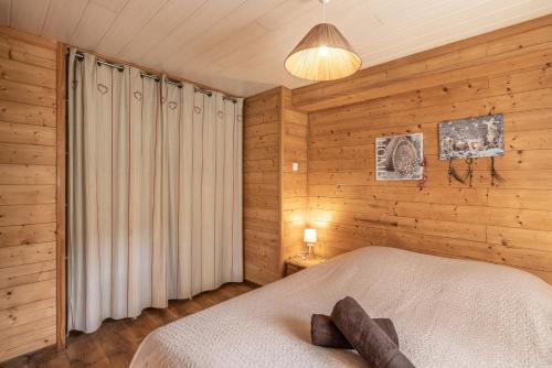 科尔顿La Charbonnière的一间带木墙的卧室和一张位于客房内的床