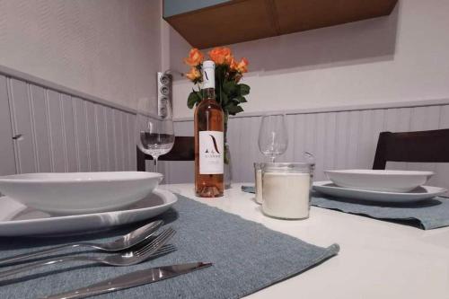 - une table avec des assiettes, des verres et une bouteille de vin dans l'établissement Mon petit chez moi, à Agde