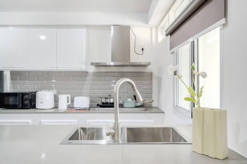 a white kitchen with a sink and a window at Haus Ekkamai 2 in Khlong Toei