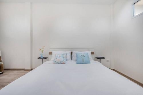 a white bed with blue pillows in a bedroom at Haus Ekkamai 2 in Khlong Toei