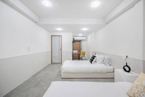 a white bedroom with two beds and a table at Haus Ekkamai 2 in Khlong Toei