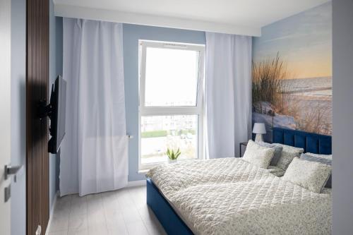 a bedroom with a bed and a large window at Apartament Morski by GoApart in Gdańsk