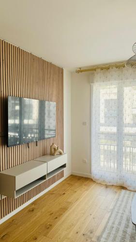 - un salon avec une grande télévision murale dans l'établissement Bel appartement à 5 mn de Paris très proche Métro 13 et 14, à Saint-Ouen